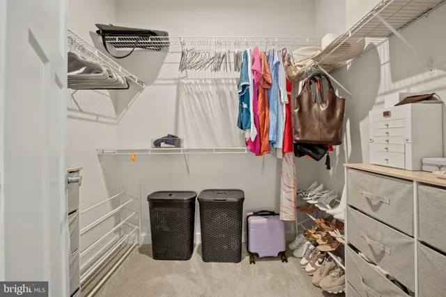 a view of walk in closet with clothes and shoes