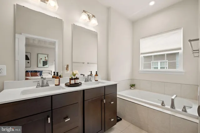 a bathroom with a tub double sink window and mirror