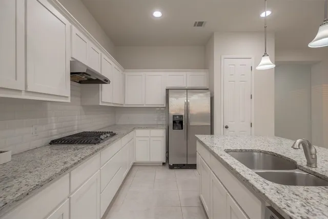 a kitchen with stainless steel appliances granite countertop a sink and a refrigerator