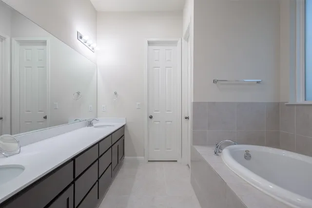 a bathroom with a tub sink shower and mirror