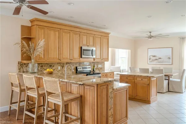 a kitchen with stainless steel appliances granite countertop a stove a sink dishwasher and a refrigerator with wooden cabinets