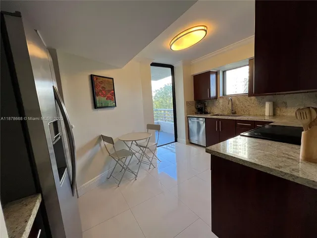 a kitchen with stainless steel appliances granite countertop a sink a stove a dining table and chairs