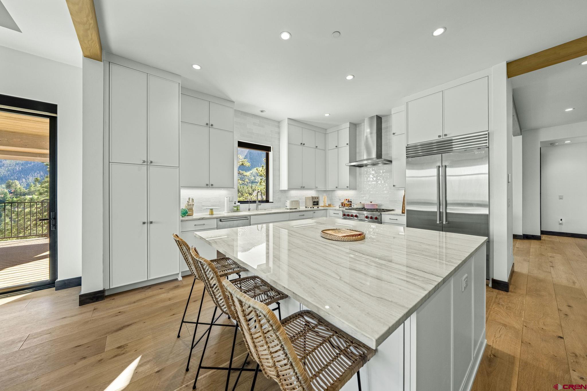 136 Outlaw Drive, Unit 3B Durango, CO 81301 - Photo 22 of 45 a kitchen with stainless steel appliances granite countertop a kitchen island a stove a sink a refrigerator and white cabinets with wooden floor