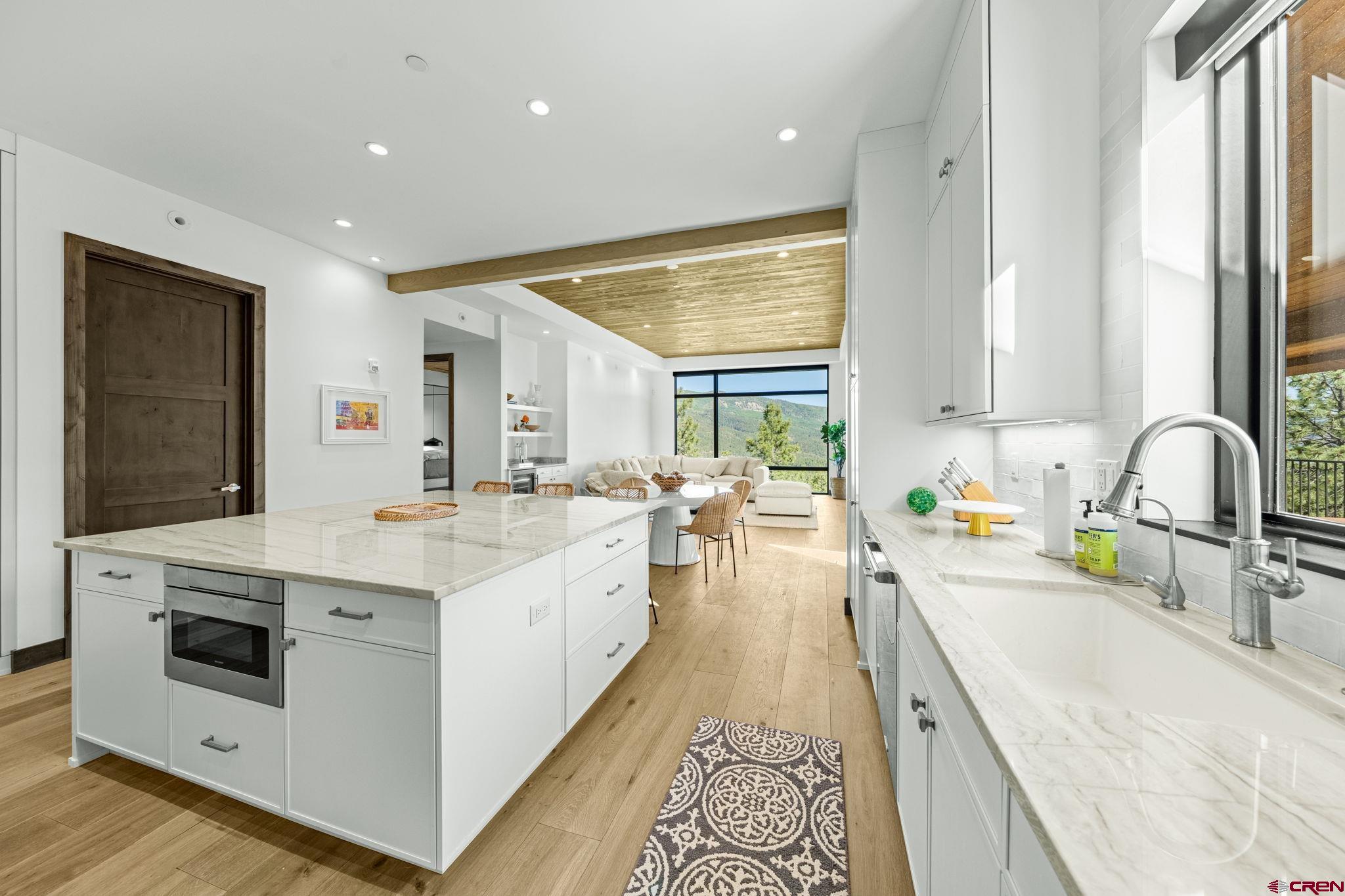 136 Outlaw Drive, Unit 3B Durango, CO 81301 - Photo 26 of 45 a large white kitchen with a stove a sink a refrigerator and a dining table with wooden floor