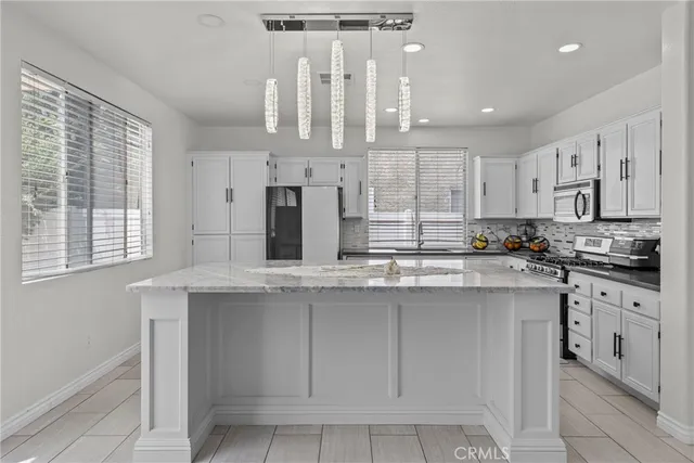 a kitchen with stainless steel appliances granite countertop a stove a sink and white cabinets