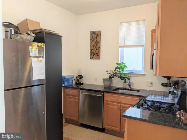 a kitchen with stainless steel appliances granite countertop a refrigerator a sink a stove a dining table and with wooden floor