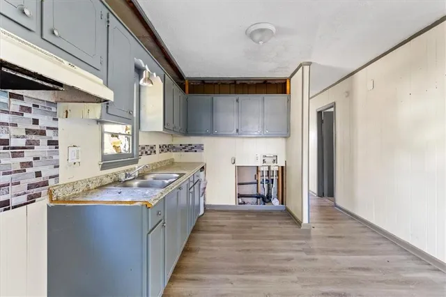 a kitchen with granite countertop a sink cabinets and wooden floor