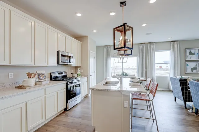 a kitchen with stainless steel appliances kitchen island granite countertop a dining table chairs stove refrigerator and cabinets