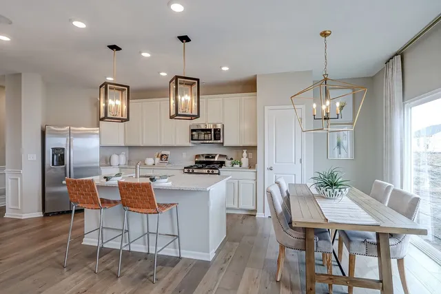 a kitchen with stainless steel appliances granite countertop a stove top oven a sink a dining table and chairs with wooden floor