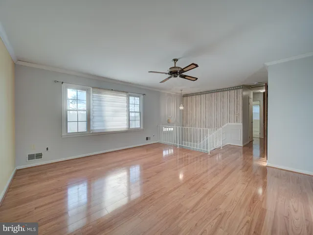 a view of empty room with wooden floor and fan