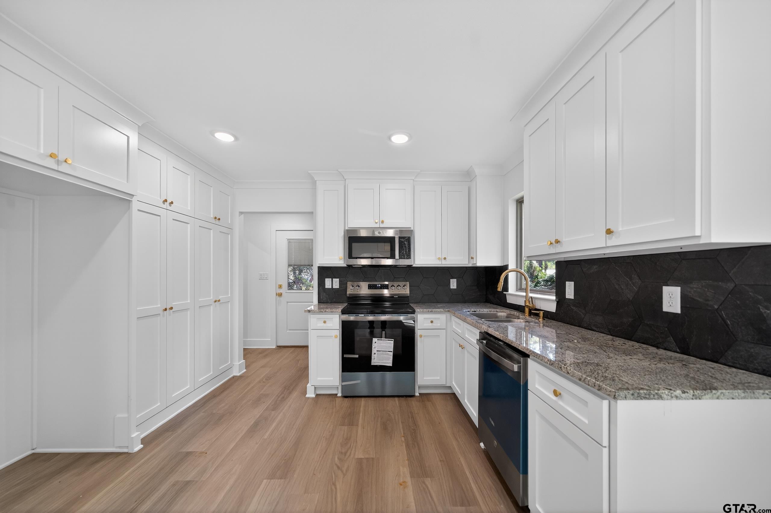 329 Wiley Drive Bullard, TX 75757 - Photo 12 of 31 a kitchen with granite countertop white cabinets and stainless steel appliances