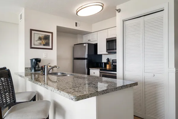 a kitchen with granite countertop a sink and a refrigerator