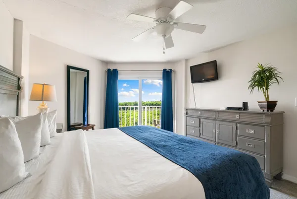 a bedroom with a large bed and a flat tv screen on dresser