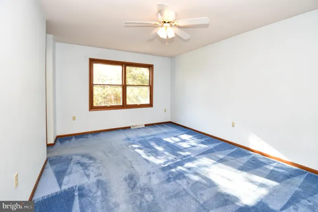 an empty room with wooden floor chandelier fan and windows