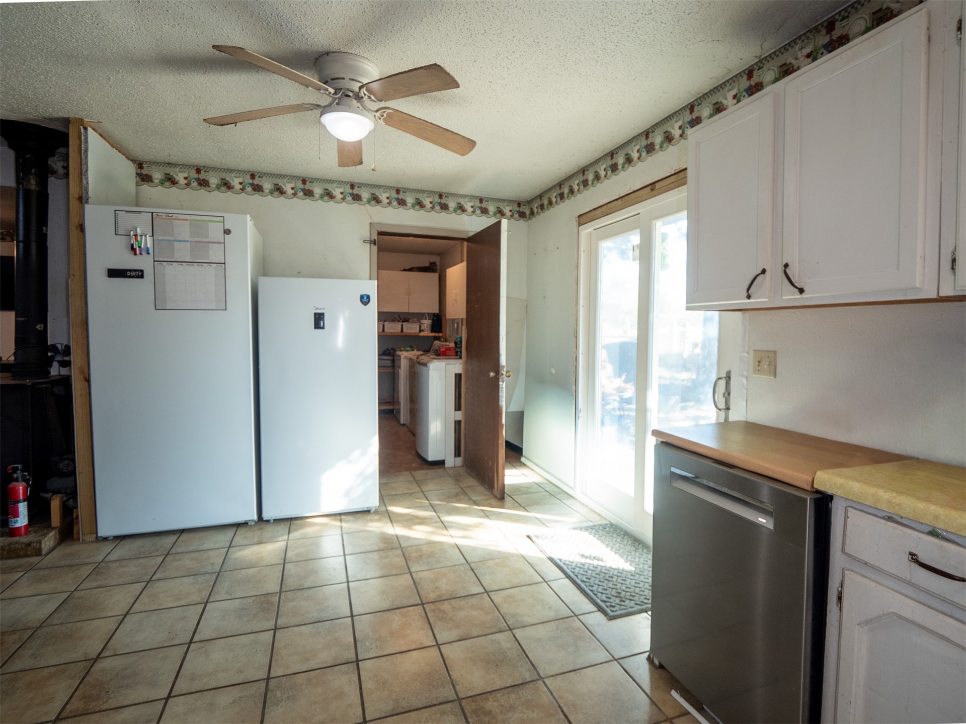 1599 North 4010 Road Boswell, OK 74727 - Photo 46 of 57 Tiled flooring, white cabinetry, wood-finish countertops, stainless steel dishwasher, and a ceiling fan with integrated lighting