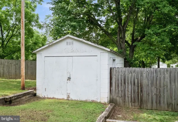 a view of a backyard with large trees and wooden fence