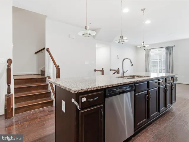 a kitchen with stainless steel appliances granite countertop a sink a stove and a wooden floors