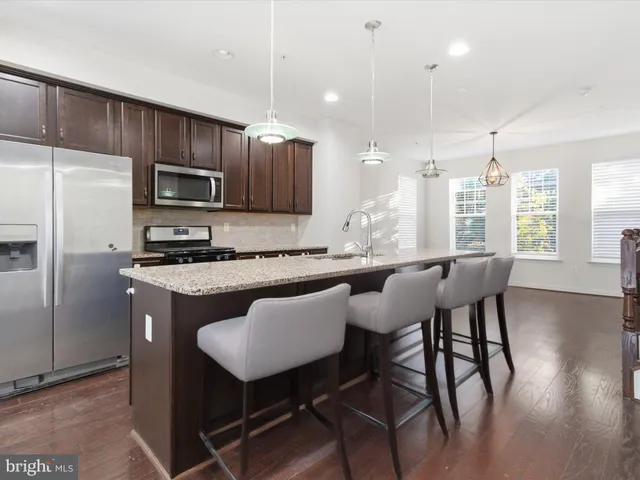 a kitchen with kitchen island granite countertop a table chairs microwave and cabinets