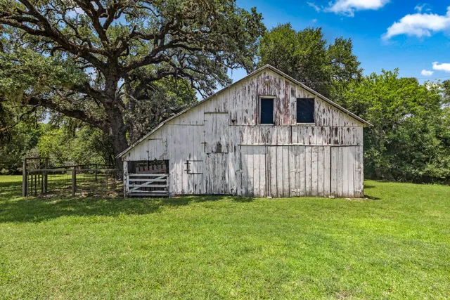 a view of a small house with yard and trees in the background