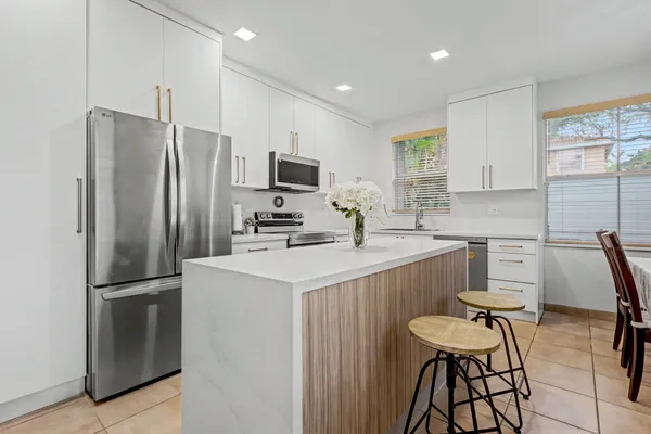 a kitchen with a refrigerator a microwave a sink and chairs