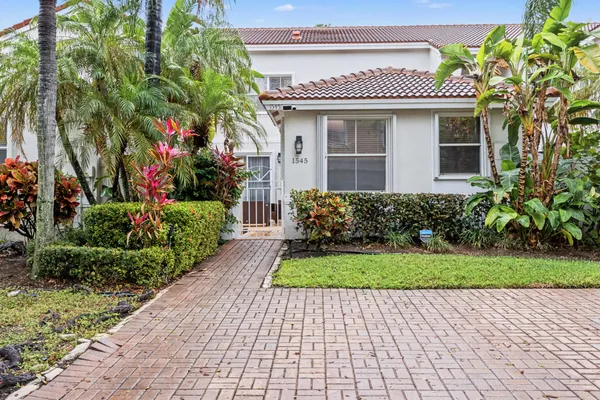 a front view of a house with a yard and potted plants