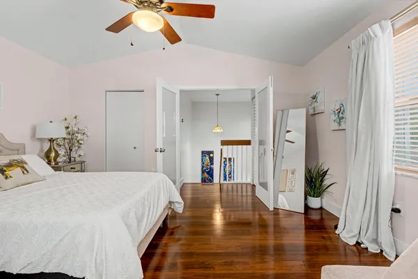 a bedroom with a bed ceiling fan and a large window