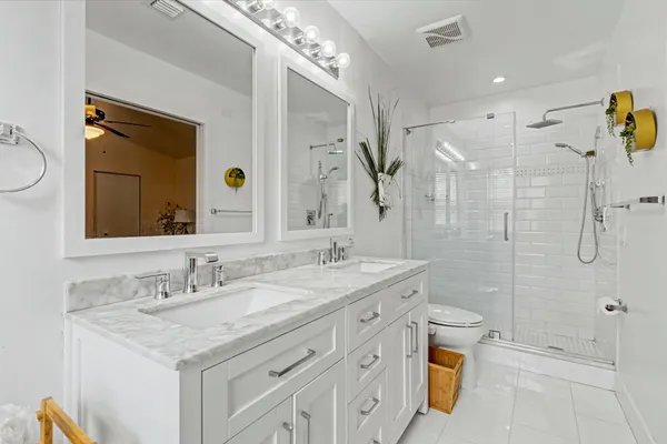 a bathroom with a granite countertop sink a toilet a mirror and shower