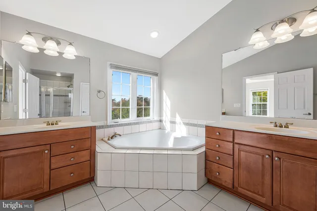a spacious bathroom with a granite countertop double vanity sink mirror and bathtub