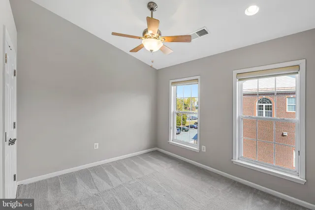 an empty room with windows and fan