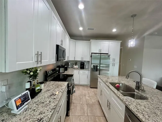 a kitchen with kitchen island granite countertop a sink counter top space appliances and cabinets