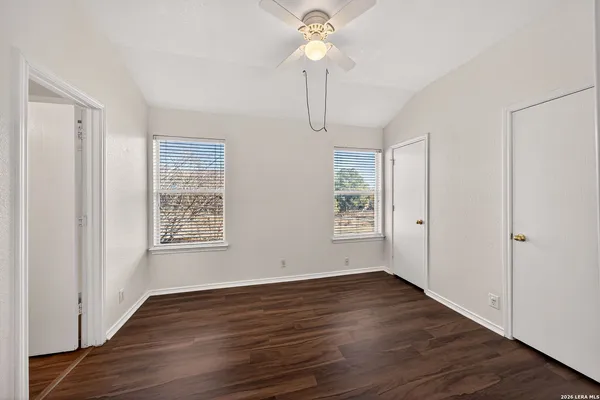 an empty room with wooden floor chandelier fan and windows