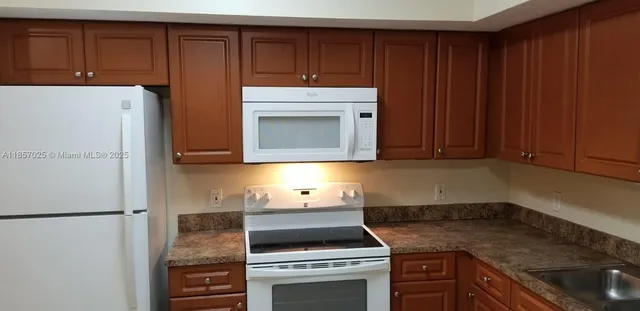 a kitchen with granite countertop cabinets and refrigerator