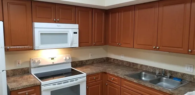 a kitchen with granite countertop a sink cabinets and stainless steel appliances