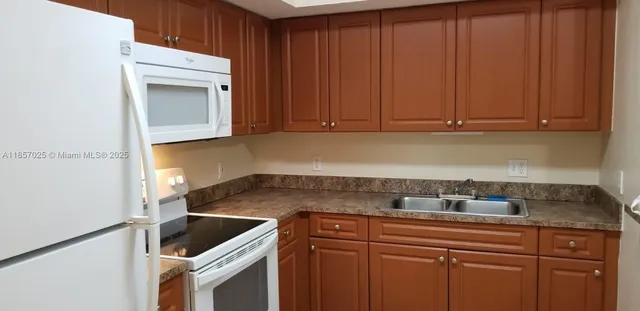 a kitchen with granite countertop a sink cabinets and stainless steel appliances