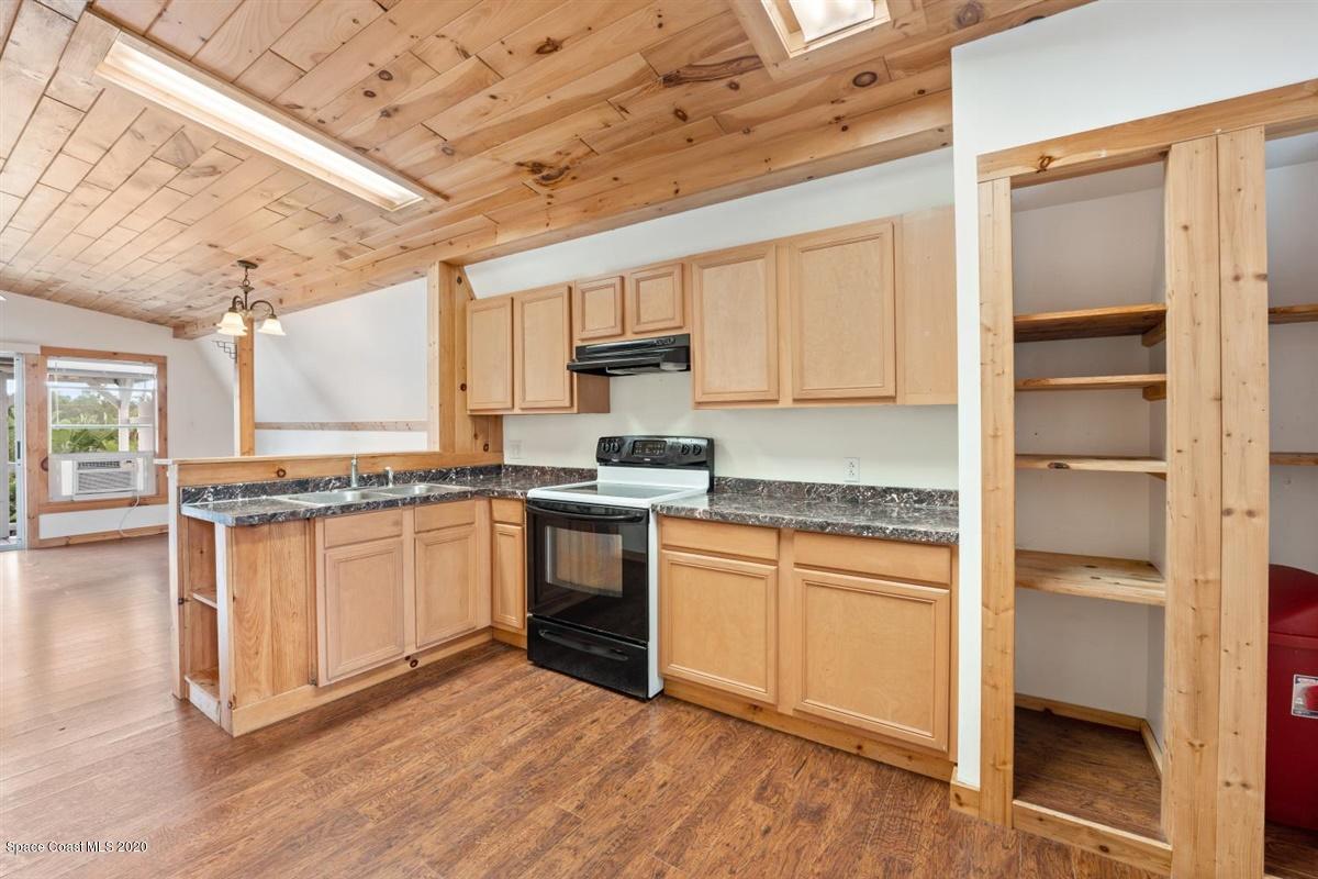 3600 Leghorn Road Grant Valkaria, FL 32950 - Photo 22 of 33 a kitchen with granite countertop a stove cabinets and wooden floor