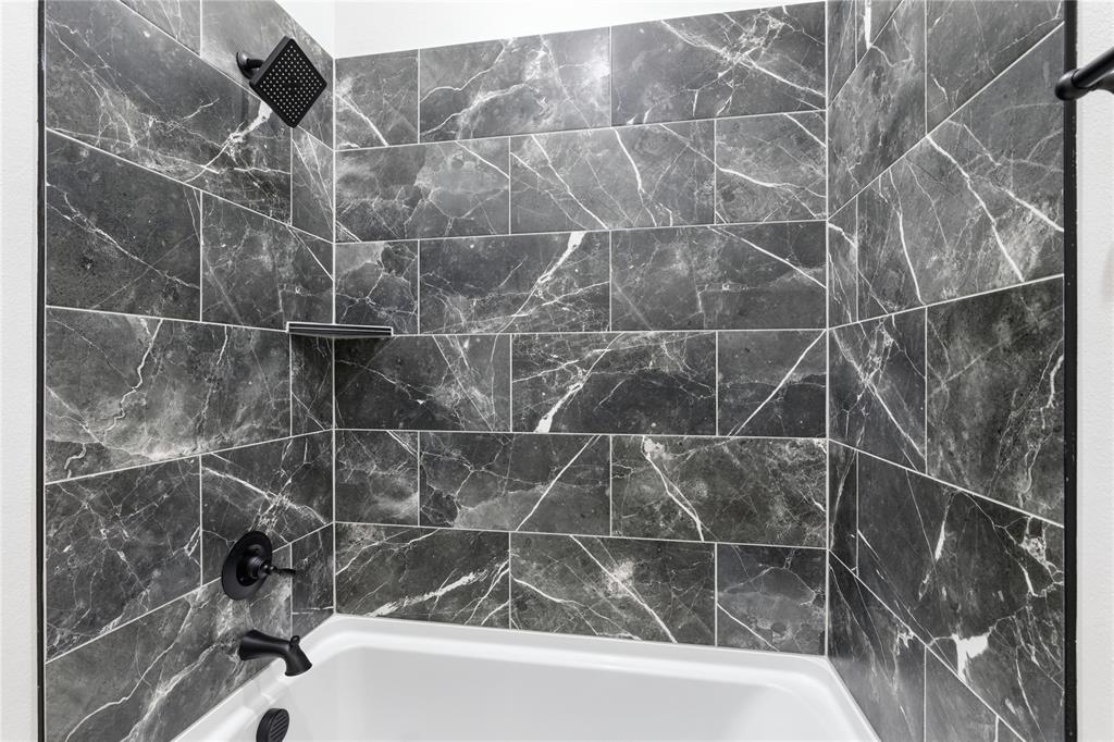 713 Anne Road Van Alstyne, TX 75495 - Photo 19 of 29 Bathtub and shower combination featuring dark-toned, large format tile with white veining