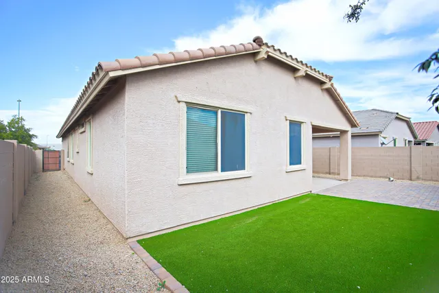 a view of a white house next to a yard and a large tree