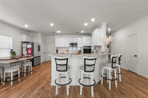 a kitchen with stainless steel appliances kitchen island granite countertop a wooden floor and white cabinets