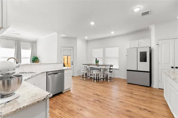 a kitchen with stainless steel appliances granite countertop a table chairs sink and cabinets