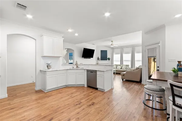 a kitchen with a sink dishwasher a dining table chairs and view living room