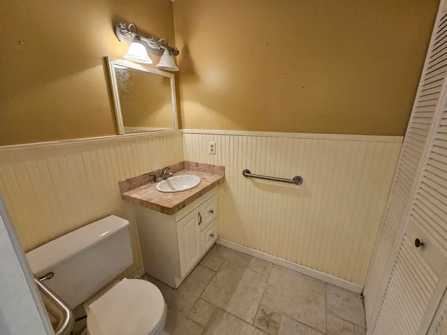 a bathroom with a granite countertop toilet sink and mirror