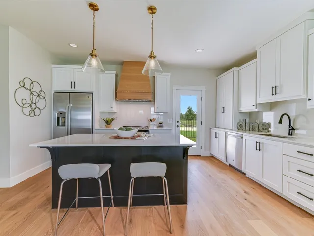 a kitchen with cabinets a sink dishwasher a dining table and chairs with wooden floor