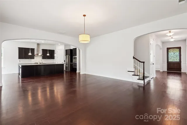 an empty room with wooden floor and kitchen view