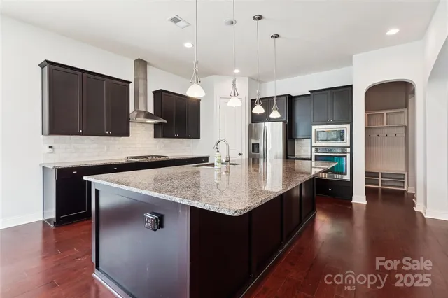 a large kitchen with a large counter top a sink stainless steel appliances and cabinets