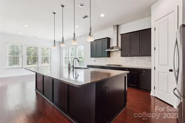 a kitchen with stainless steel appliances granite countertop a sink a stove and a wooden floors