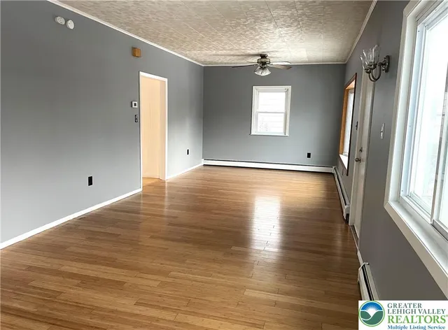 a view of an empty room with wooden floor and a window
