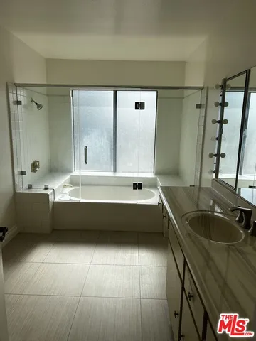 a bathroom with a tub a sink and a large mirror