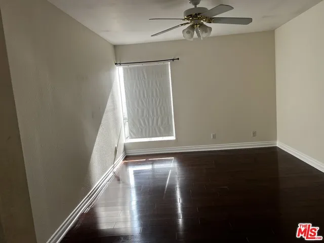 an empty room with wooden floor fan and windows