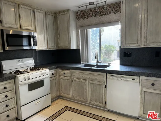 a kitchen with granite countertop white cabinets and white appliances