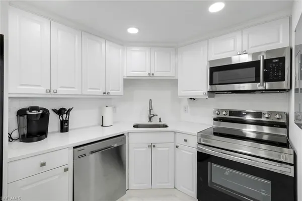 a kitchen with cabinets stainless steel appliances and sink